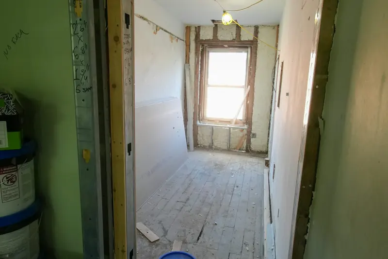 Une pièce en travaux avec un sol, des murs et une porte inachevés.